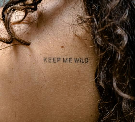 Lettrage « Keep me wild » sur le dos (tatouage lettrage)
