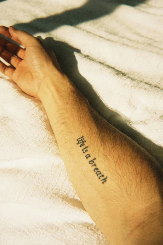 Citation « Life is a breath » sur le bras (tatouage lettrage)