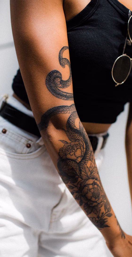 Serpent et fleurs sur le bras (tatouage blackwork)
